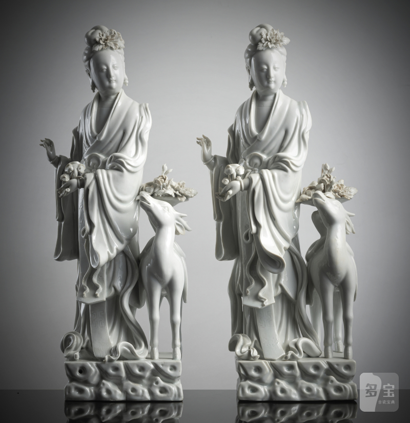A pair of exquisite Dehua figurines depicting Magu with a deer, standing on a cloud-shaped pedestal with a basket of flowers